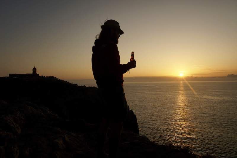 Chris en "RandomSunset Beer O'Clock" con el faro en el acantilado del cabo de São Vicente