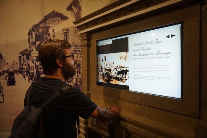 Chris aprendiendo sobre como surgieron los trishaws en Penang, con un panel interactivo del Museo