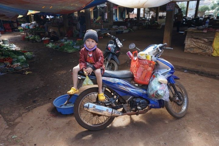 Un niño encima de la moto de su padre en el mercado
